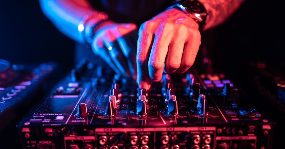 Close up of DJ hands mixing music on a table. DJ in a night club.